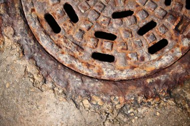 Güzel renkler ve dokularla kaplı paslı rögar kapağı.