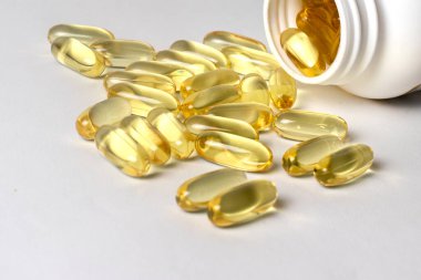 Beyaz bir kavanozda sarı omega-3 kapsülleri. Balık yağının sağlık yararları.