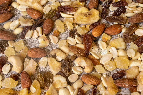 Mix of nuts and dried fruits on a stone gray background. Peanuts, candied pineapples, raisins, dried bananas, figs, almonds.