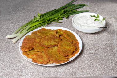 Büyük bir tabak patatesli gözleme ve ekşi kremalı, otlu ve taze yeşil soğanlı bir tabak..