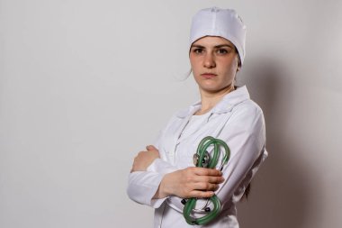 Yeşil steteskop. Beyaz üniformalı bir doktor stetofondoskop tutuyor.