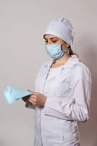 戴着医疗面罩和白衣的医生带着许多医疗保护面罩 — 图库照片