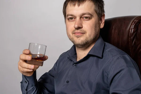一个30岁的男人手里拿着杯子里的威士忌 昂贵的酒精饮料 — 图库照片
