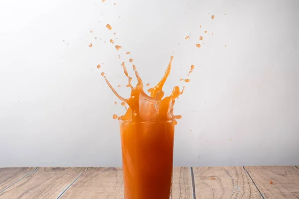 Orange juice is sprayed from a glass. Spray a sweet drink. A splash of fruit juice.