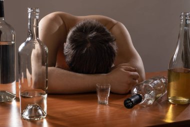 Sarhoş adam ve boş şişeler. Alkolizm, bağımlılık, kriz ve depresyon.