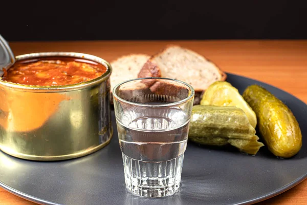 A glass of vodka and an appetizer for alcoholic drinks (canned sprats, pickled cucumbers and bread). — Stock Image Glass Vodka Appetizer Alcoholic Drinks Canned Sprats Pickled Cucumbers Bread Royalty Free Stock Images