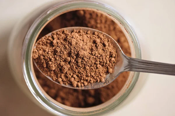 Kavanoz ve kaşıkta kakao tozu. Yiyecek malzemesi.