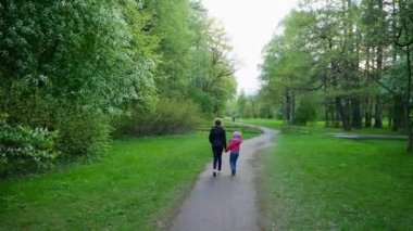 Genç bir kız ve bir kız el ele tutuşarak parkta yürüyorlar. Çiçek açan kiraz ağaçlarının etrafında. Mayıs ayında St. Petersburg 'da Kültür ve Eğlence Parkının Yelagin Adası' nda lale festivali..