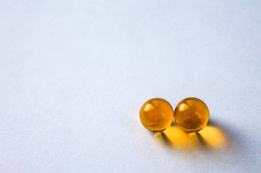 Sarı vitamin kapsülleri Omega 3 yağ asitleri bağışıklık ve hastalık önleme için izole edilmiş beyaz bir zemin üzerinde yatar.