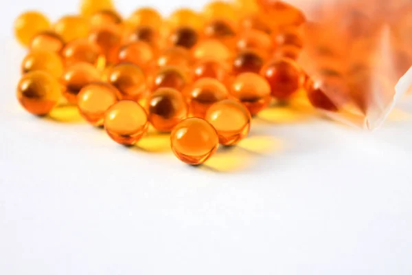 Yellow capsules of vitamins omega 3 fatty acids lie on a table on a white background isolated for immunity and disease prevention