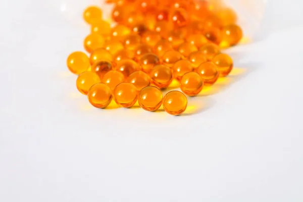 Sarı vitamin kapsülleri Omega 3 yağ asitleri bağışıklık ve hastalık önleme için izole edilmiş beyaz bir zemin üzerinde yatar.