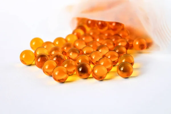 Sarı vitamin kapsülleri Omega 3 yağ asitleri bağışıklık ve hastalık önleme için izole edilmiş beyaz bir zemin üzerinde yatar.