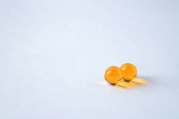 Sarı vitamin kapsülleri Omega 3 yağ asitleri bağışıklık ve hastalık önleme için izole edilmiş beyaz bir zemin üzerinde yatar.