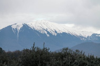 Sınır kulesinin arka planında karla kaplı yüksek dağlar var.