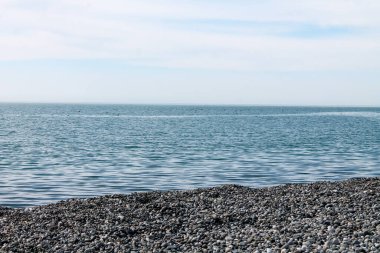 Sakin mavi deniz çakıl taşı plajı berrak gökyüzü parlak ışık