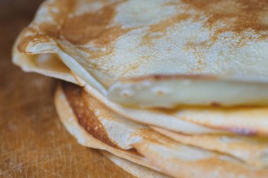 Ahşap bir tahtanın üzerinde taze pişmiş krep yığını.