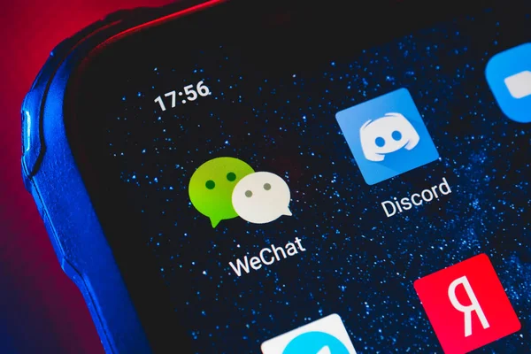 stock image WeChat app icon on the screen smartphone. WeChat is a Chinese multi-purpose messaging, social media and mobile payment app.