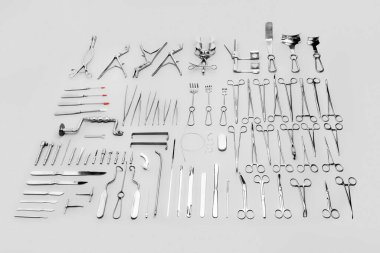 Cerrahi operasyonlarda kullanılan tıbbi gereçler, gri bir arka planda sergileniyor.