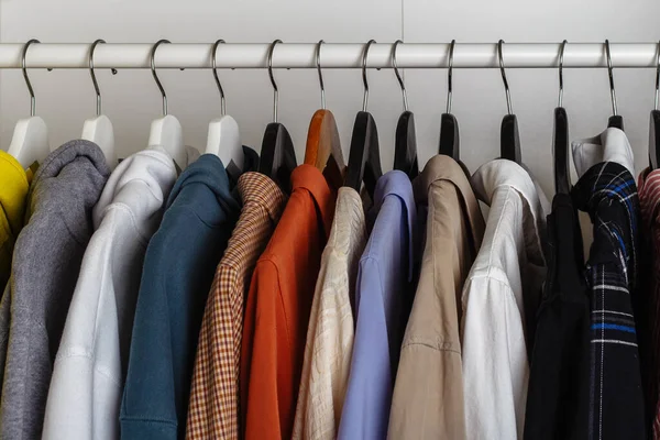 Close-up view of clothes hung on hangers in the dressing room on the white bar