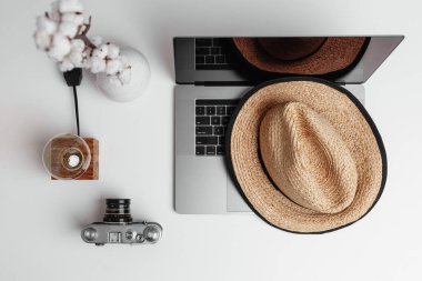 Bir vazo pamuk çiçek, eski moda kamera ve lamba, hasır şapka, bir defter.