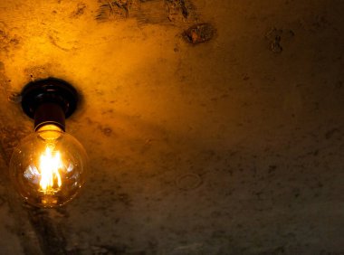 Tavandaki kahverengi arka planda bir elektrik lambası parlıyor..