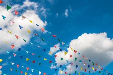 Bulutlu mavi gökyüzüne karşı çok renkli bayraklar.