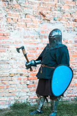 Zırhlı bir ortaçağ şövalyesi elinde balta ve kalkanla. Taklit, askeri operasyonların restorasyonu, kavgalar.