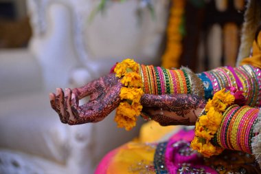 Then Pakistani bridal showing mehndi hand and colorful bangles jewelry with yellow flowers. Mehandi ceremony close-up shoot of bridal clipart