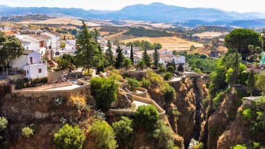 Evlerin, vadilerin, tarlaların ve ufuktaki dağların üzerindeki Ronda şehrinin panoramik manzarası