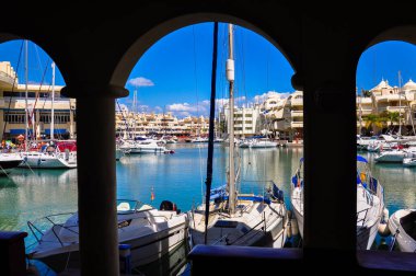 İspanya 'nın Benalmadena limanına giden kemerden deniz kenarındaki evlere ve yatlara bakın.