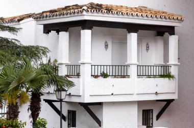 Koyu ahşap elementleri, fayanslı çatısı ve yeşil bitkileri olan tipik bir Beyaz Saray İspanyol balkonu.