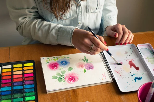 Lady mixing colors during a roses painting session using watercolor technique from high-angle shot