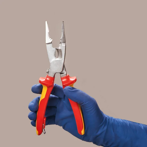 Hand in blue glove holds open pliers electrician