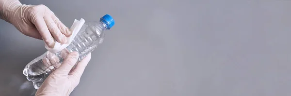 Mano en guante blanco sosteniendo la botella de gel desinfectante . — Foto de Stock