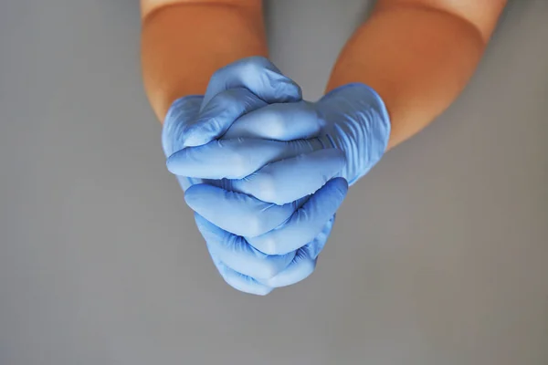 Hands clasped in blue and mint glove. Grey background — Stock Photo, Image