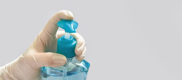 Hand in white glove holding bottle of sanitizer gel. — Stock Photo, Image