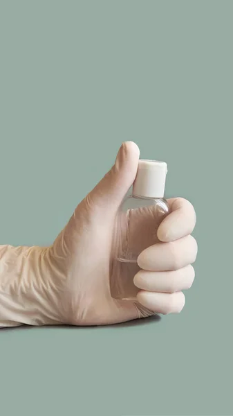 Mano en guante blanco sosteniendo la botella de gel desinfectante . — Foto de Stock