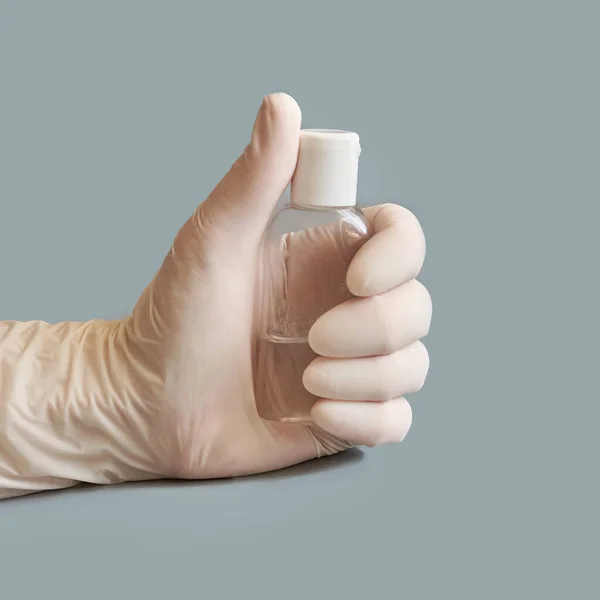 Hand in white glove holding bottle of sanitizer gel. — Stock Photo, Image