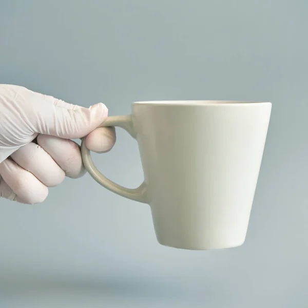 Hand in white glove holding cup of tea