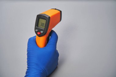 Mavi eldivenli el, termometreyi yüksek ısıda tutar.