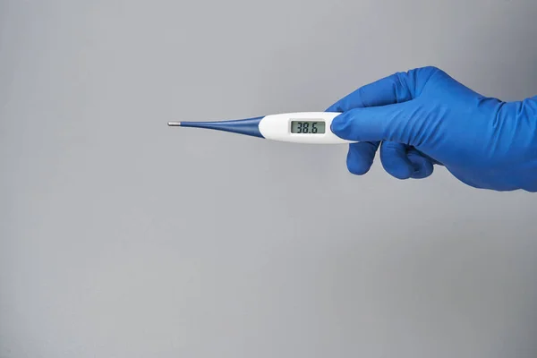 hand in blue glove holds thermometer high temperature