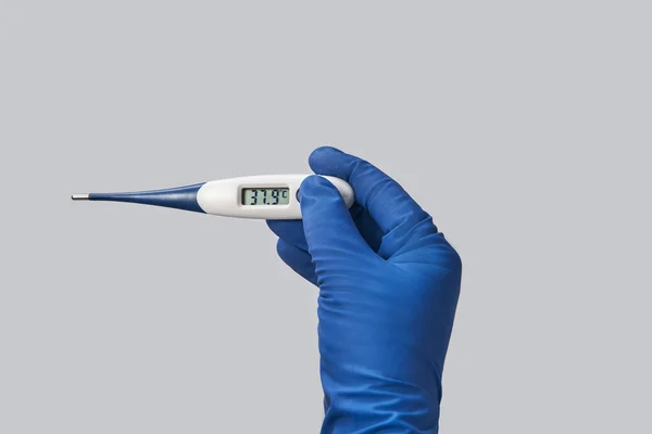 hand in blue glove holds thermometer high temperature