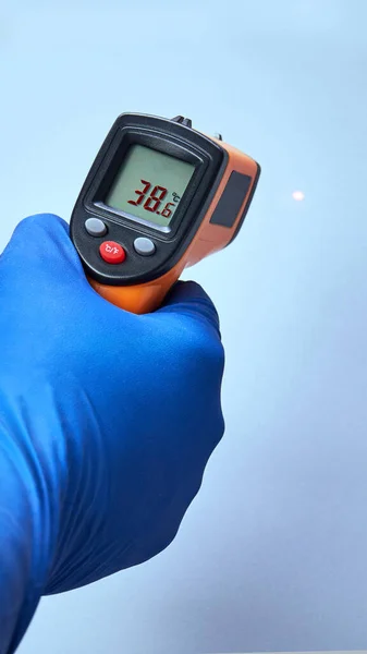 Handen i blå handske håller ir termometer hög temperatur — Stockfoto