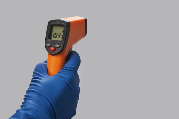 Hand in blauwe handschoen houdt ir thermometer hoge temperatuur — Stockfoto