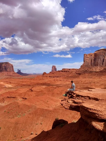 Navajo Kabile Parkı 'ndaki Anıt Vadisi' nde bir taşın üzerinde oturan bir adam.