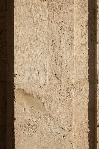 A cross inscribed in a circle engraved on the stone surface of one of the pillars of the Palladian Basilica in Vicenza. The engraving seems to have a very old style. Ancient architecture. Italy.