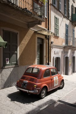 Klasik bir kırmızı Fiat 500 arabası Como Gölü yakınlarındaki geleneksel bir İtalyan caddesinde park edilmiş, Lombardy, İtalya - 29 Ağustos 2011