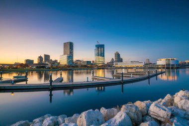 Milwaukee silueti alacakaranlıkta Michigan Gölü ve rıhtımında şehir yansıması ile.