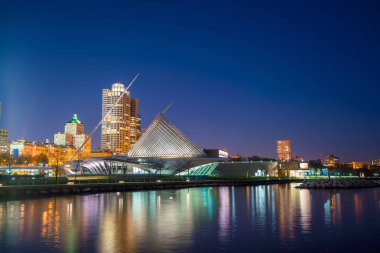 Milwaukee silueti alacakaranlıkta Michigan Gölü ve rıhtımında şehir yansıması ile.