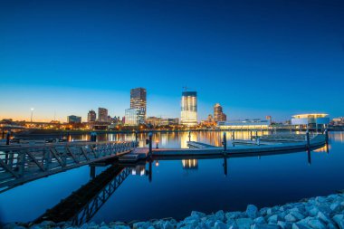 Milwaukee silueti alacakaranlıkta Michigan Gölü ve rıhtımında şehir yansıması ile.